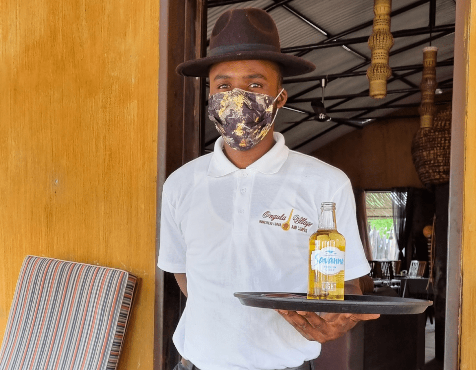 a man wearing a mask and hat standing in front of a wooden table